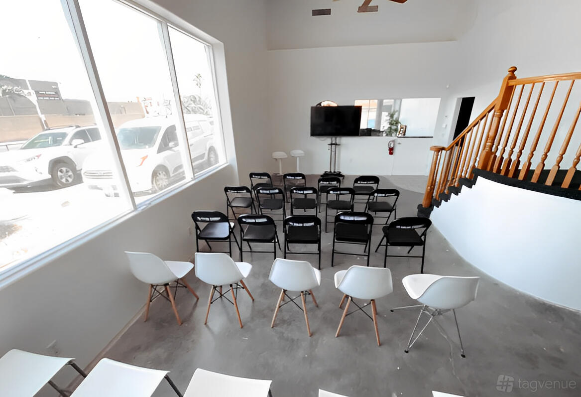A photo studio with folding chairs, white molded plastic chairs, large windows, and a TV screen at In Color Studios.