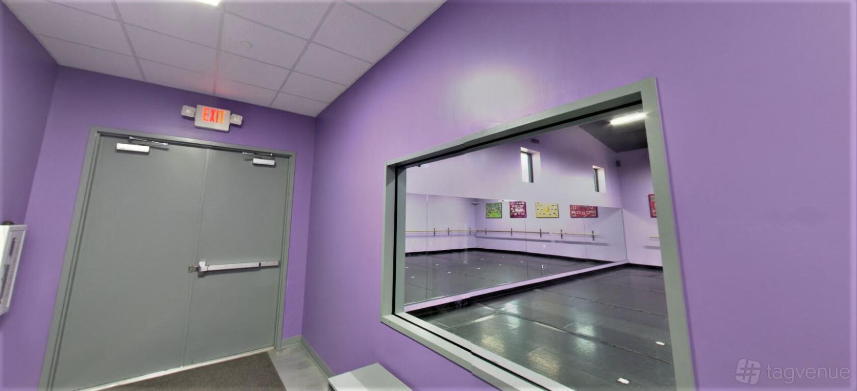An event space in a dance studio with purple walls, a large window, and wall mirrors at Dance Expressions.