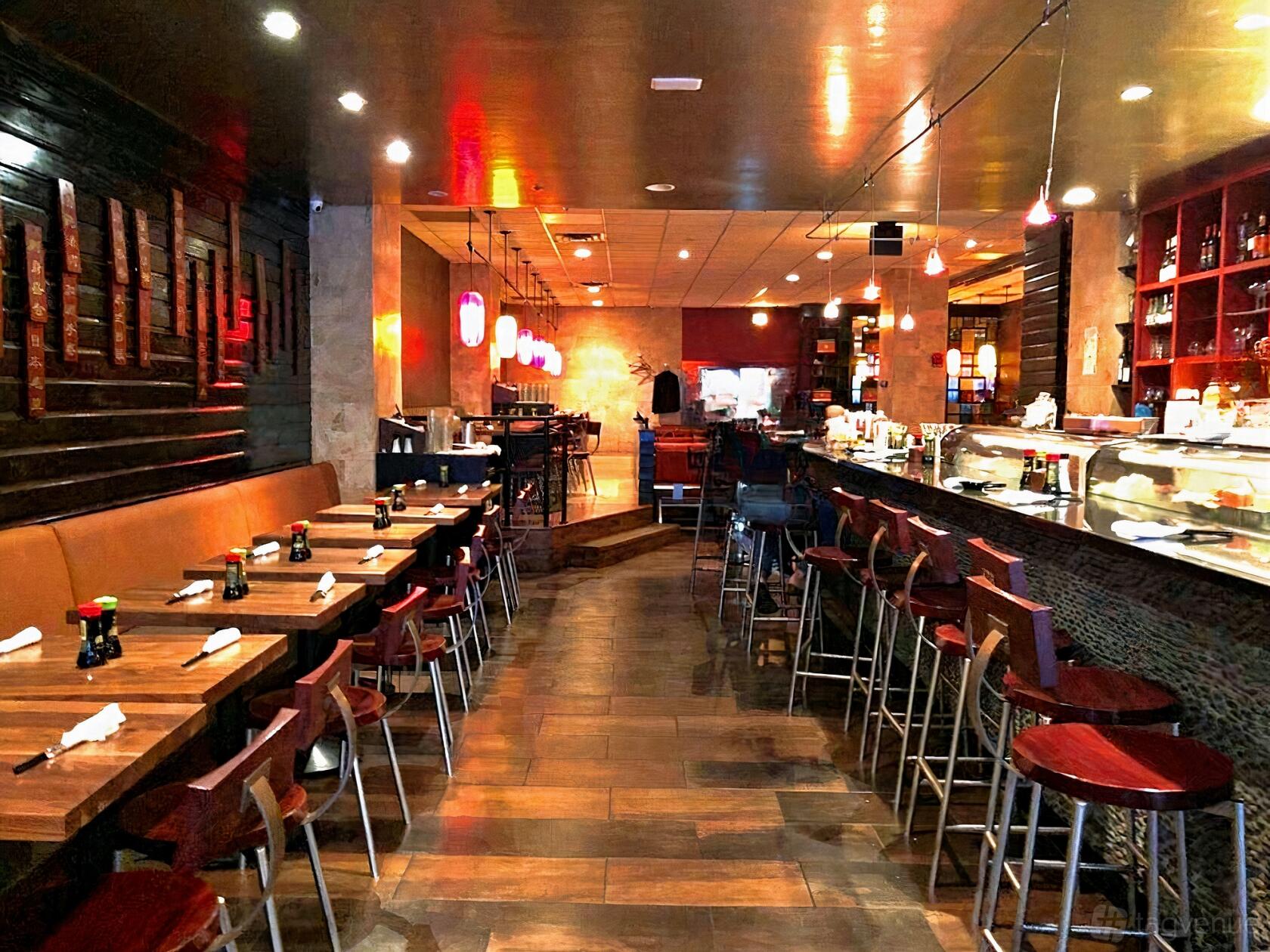 A restaurant with wooden tables, sushi bar seating, and pendant lighting at Nooshi 19th Street.