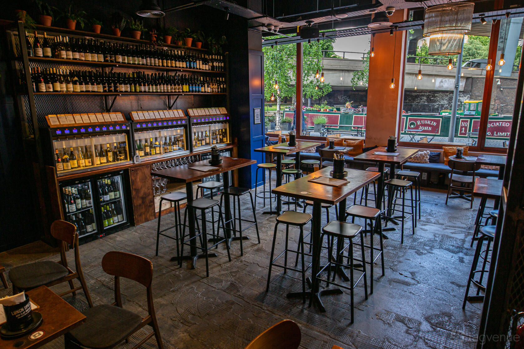 An event space in a bar with high tables, wine dispensers, and floor-to-ceiling windows at Vagabond Paddington.