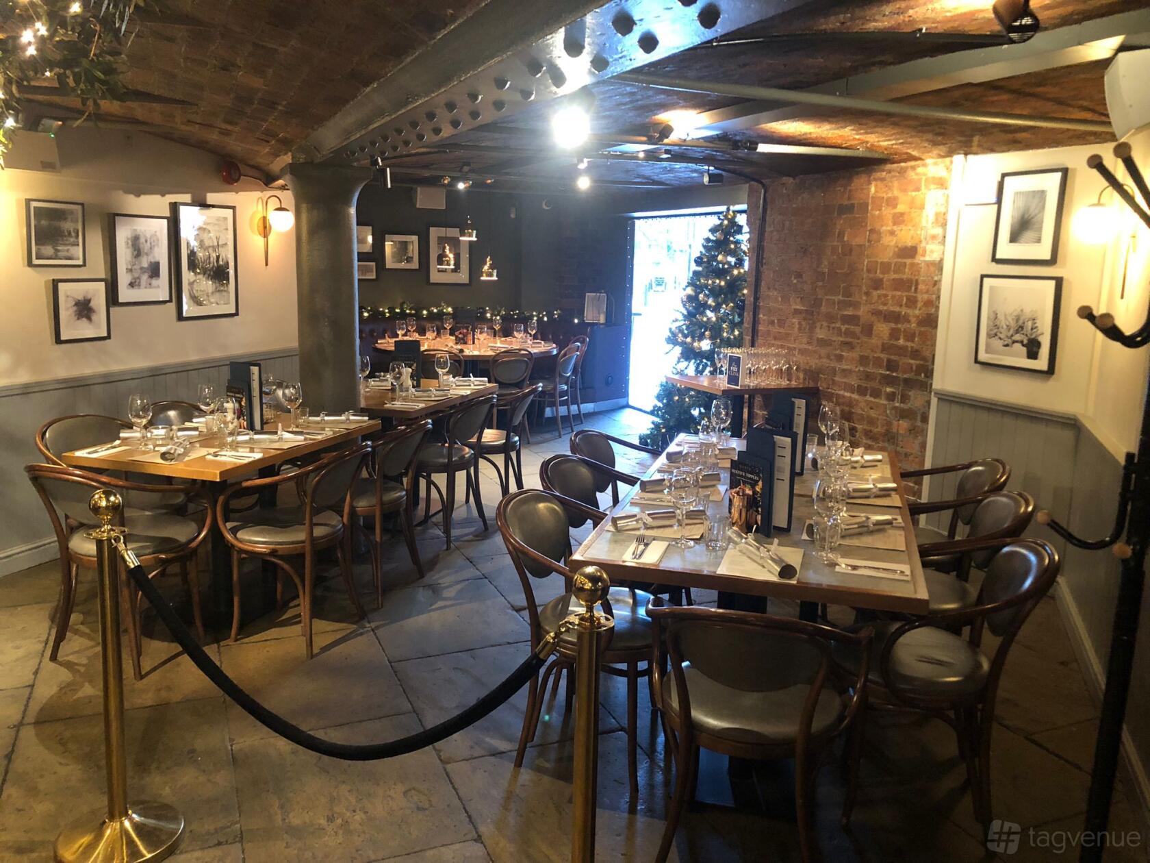 An event space with exposed brick walls, framed artwork, and set dining tables at Gusto Italian Liverpool.