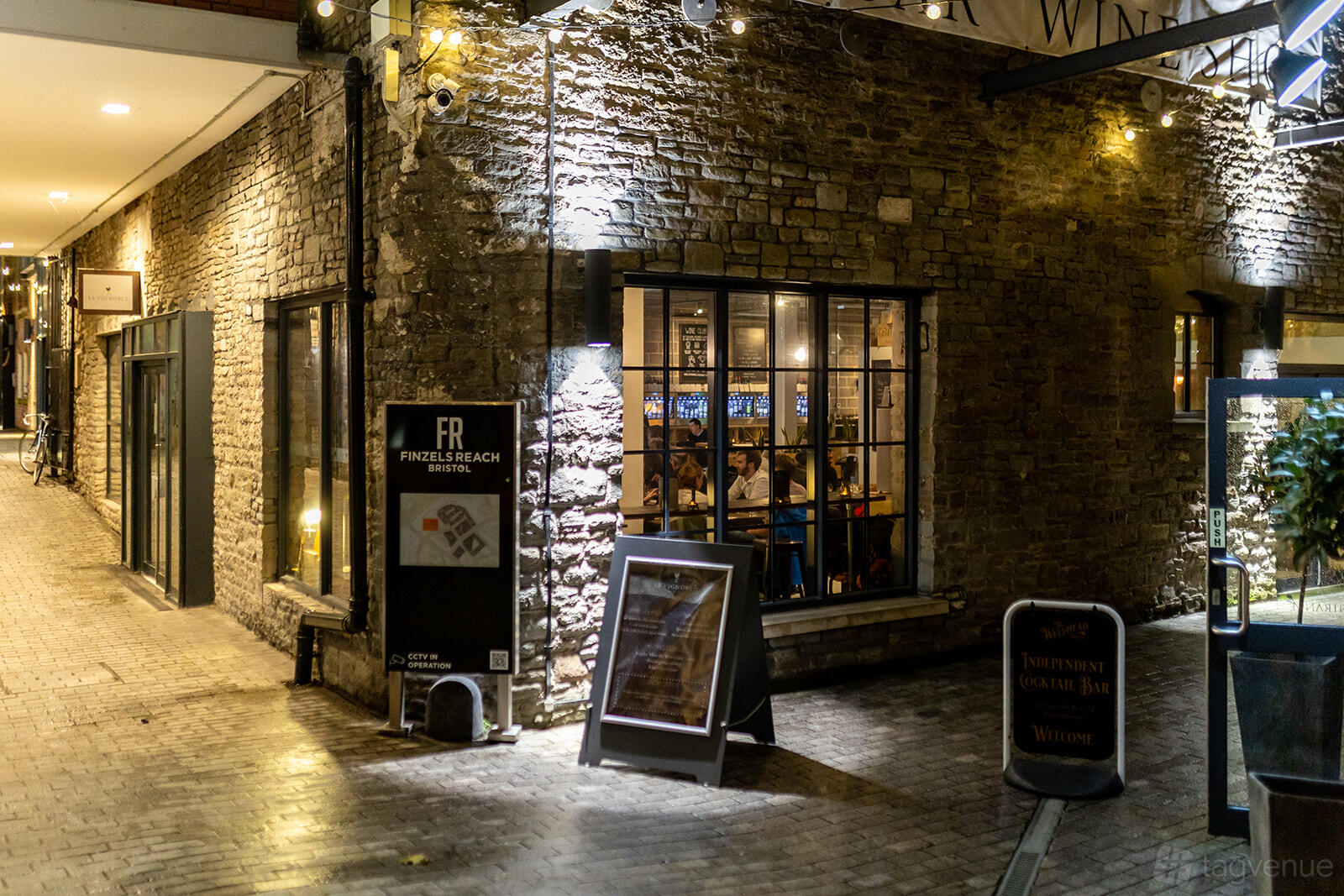 A restaurant with stone exterior walls, large windows, and warm indoor lighting at Le Vignoble Bristol.