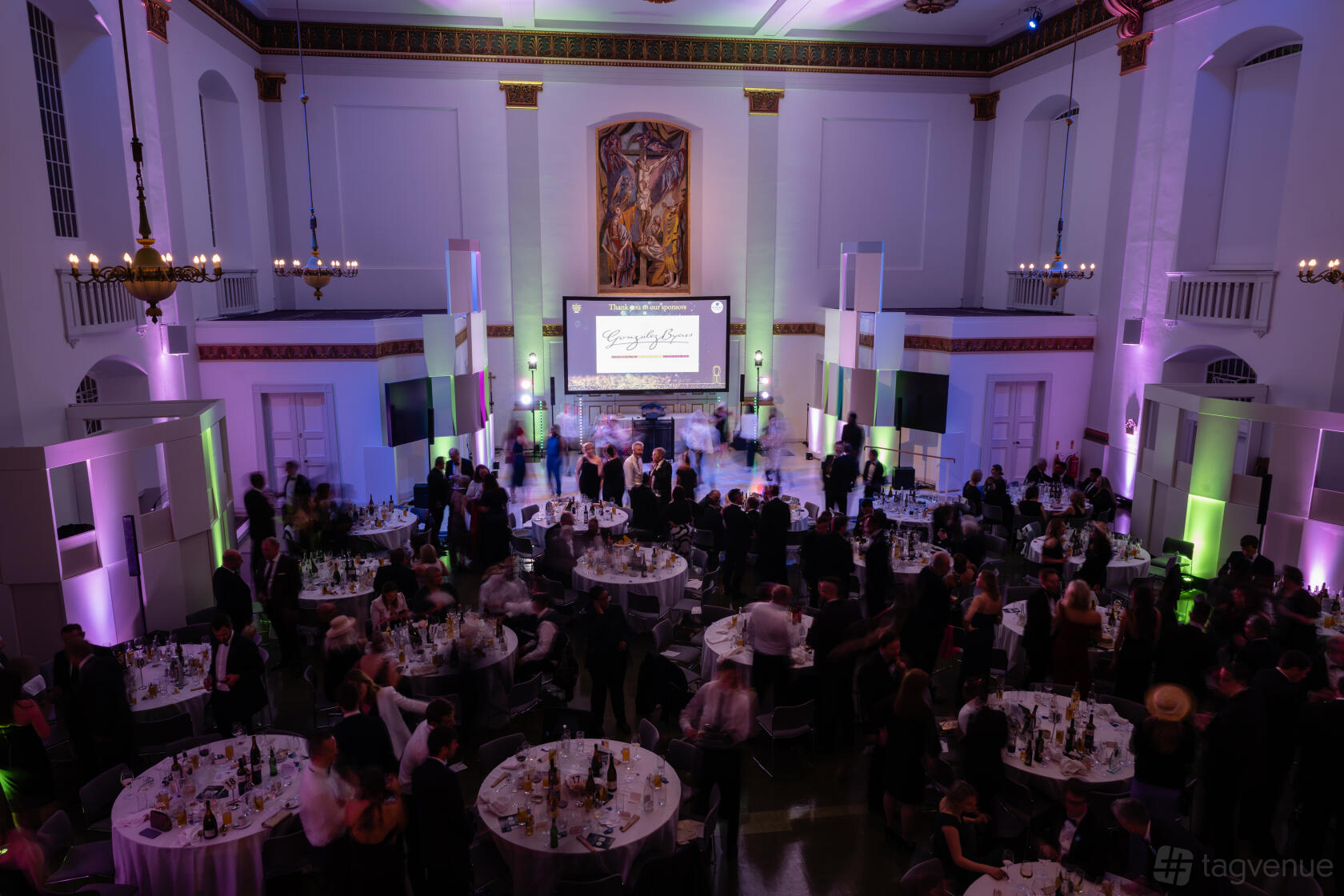 An event venue with high ceilings, round tables, chandeliers, and uplighting at 73 Waterloo at St John's.