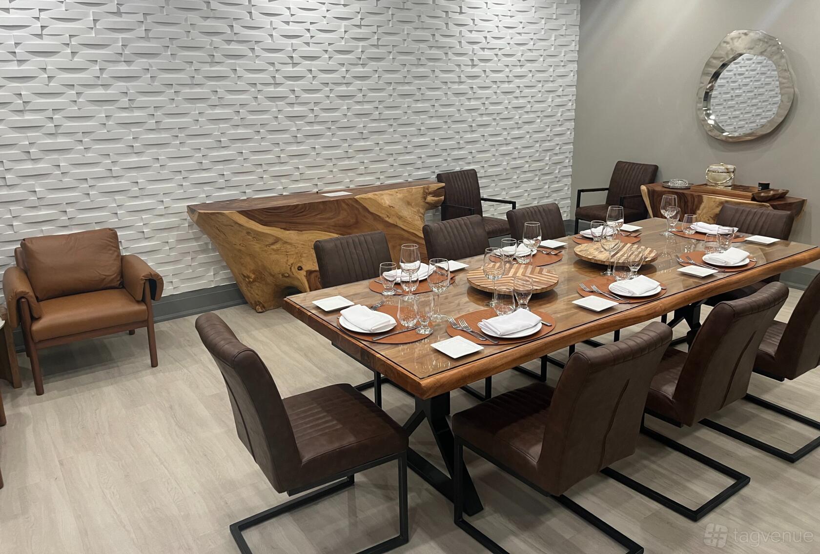 A dining room with a long wooden table, brown leather chairs, and textured white accent wall at Trimani Ristorante.