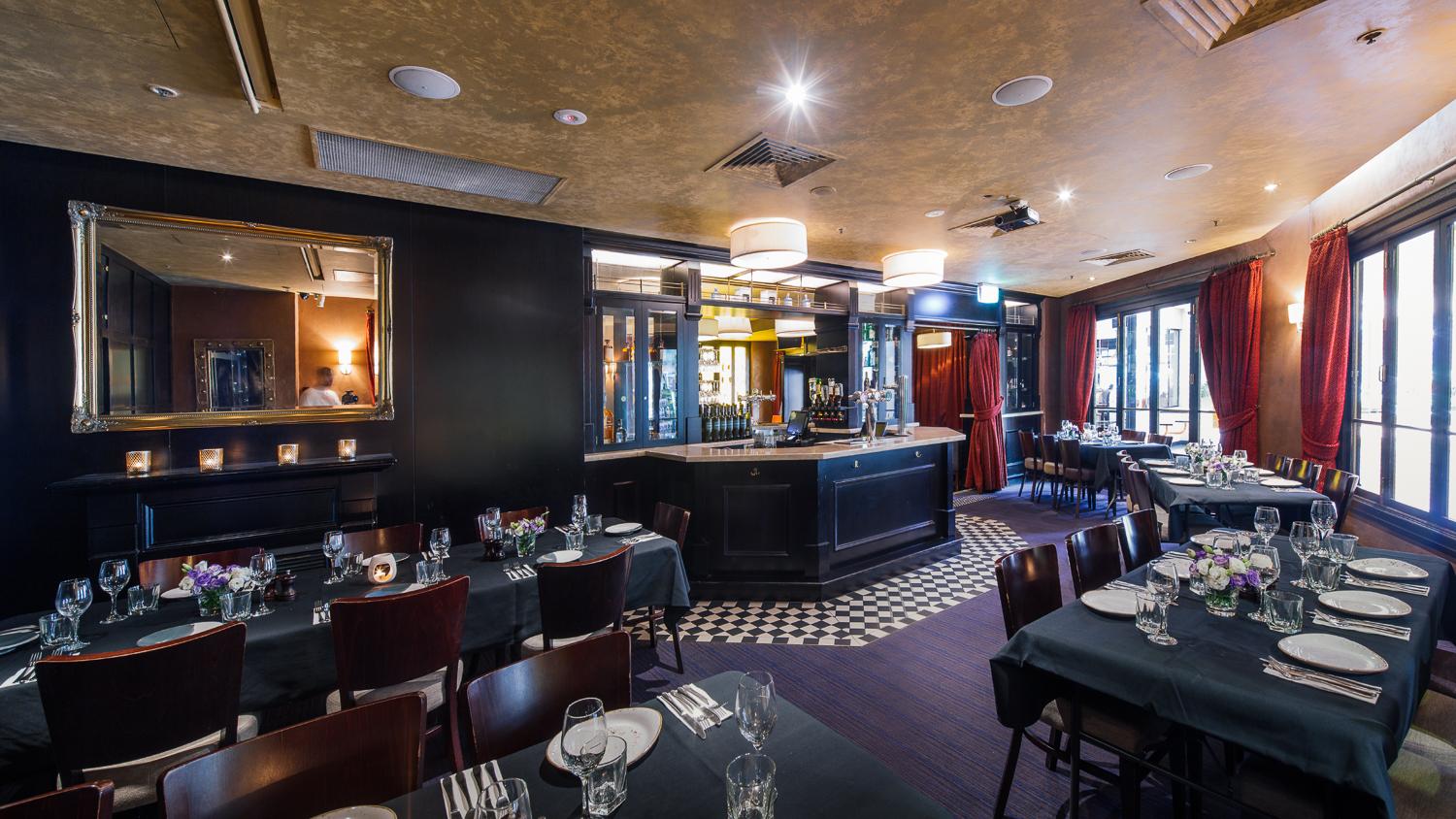 A pub lounge with dark wood furniture, candlelit tables, and a central bar area at P.J. O'Brien's Southgate.