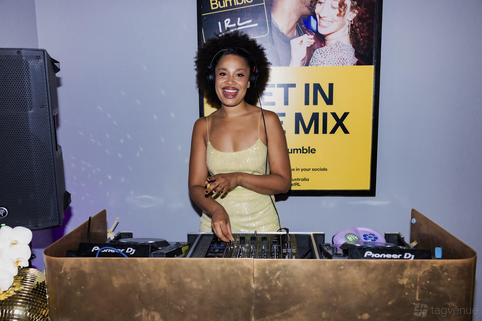 A pub DJ booth with gold accents and a smiling DJ playing music at The Tilbury Hotel.