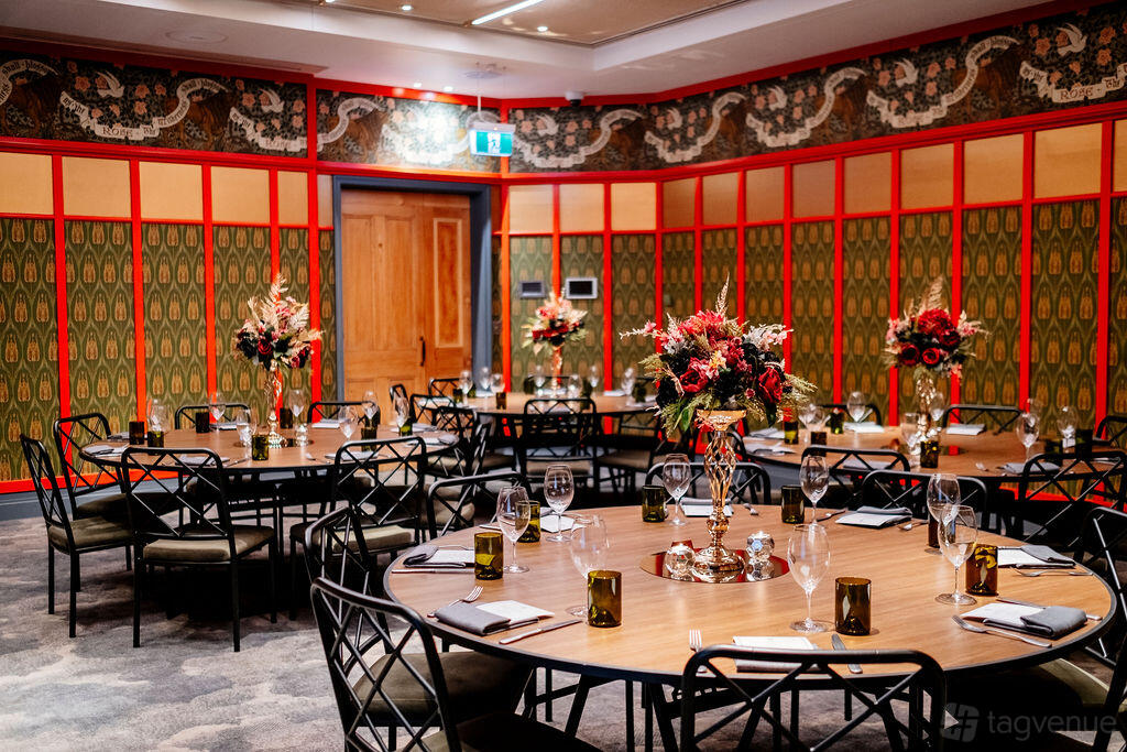 A function room with round tables, floral centerpieces, patterned wallpaper, and decorative wall panels at Ovolo The Valley.