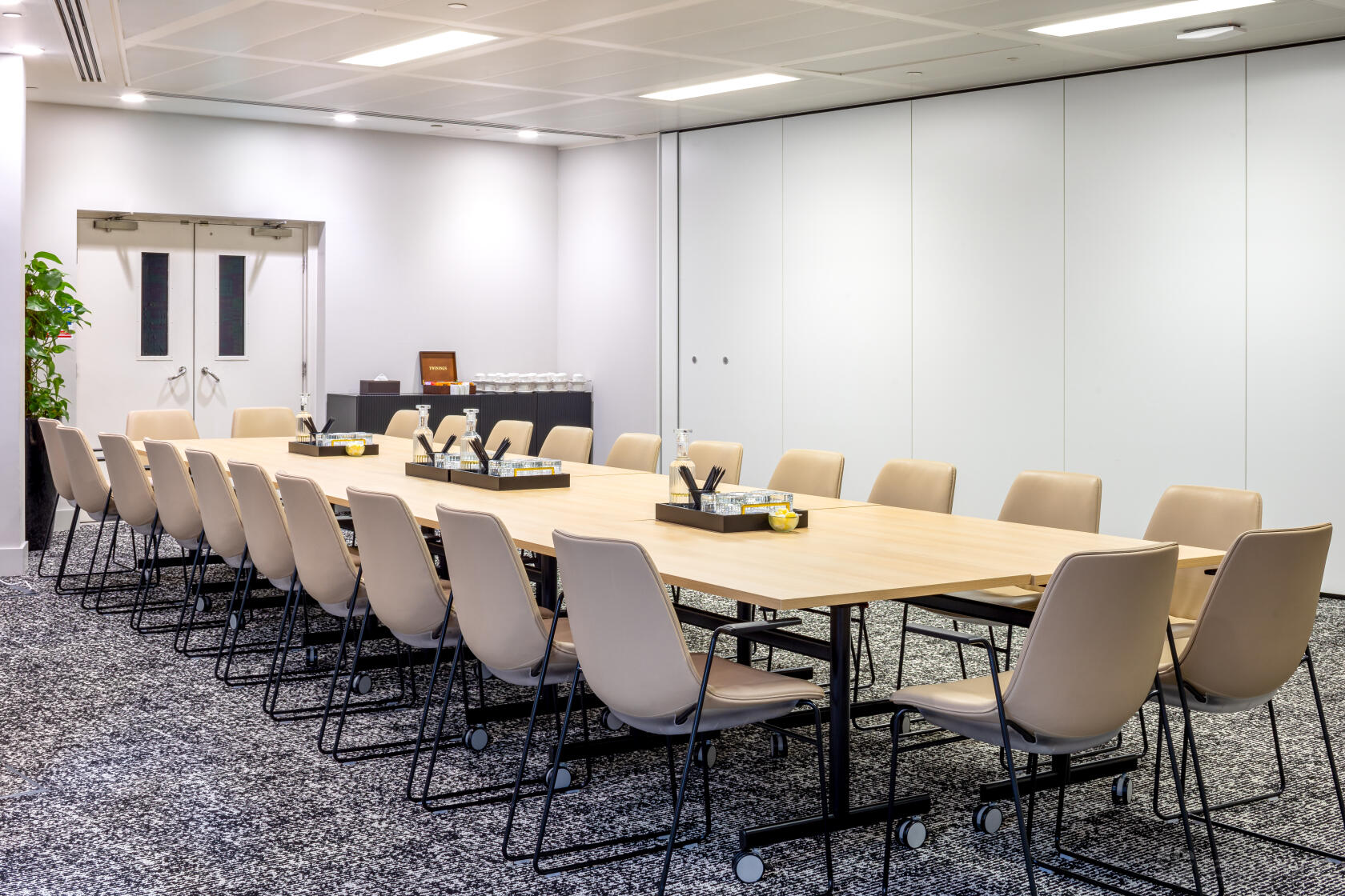 A meeting room with a long rectangular table, beige chairs, and carpeted flooring at Landmark: 99 Bishopsgate, London.