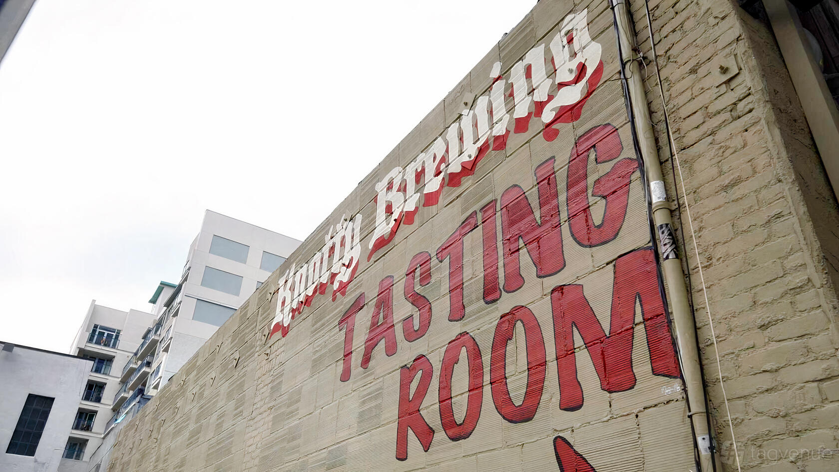 An exterior wall with bold painted signage for the Knotty Barrel Tasting Room.