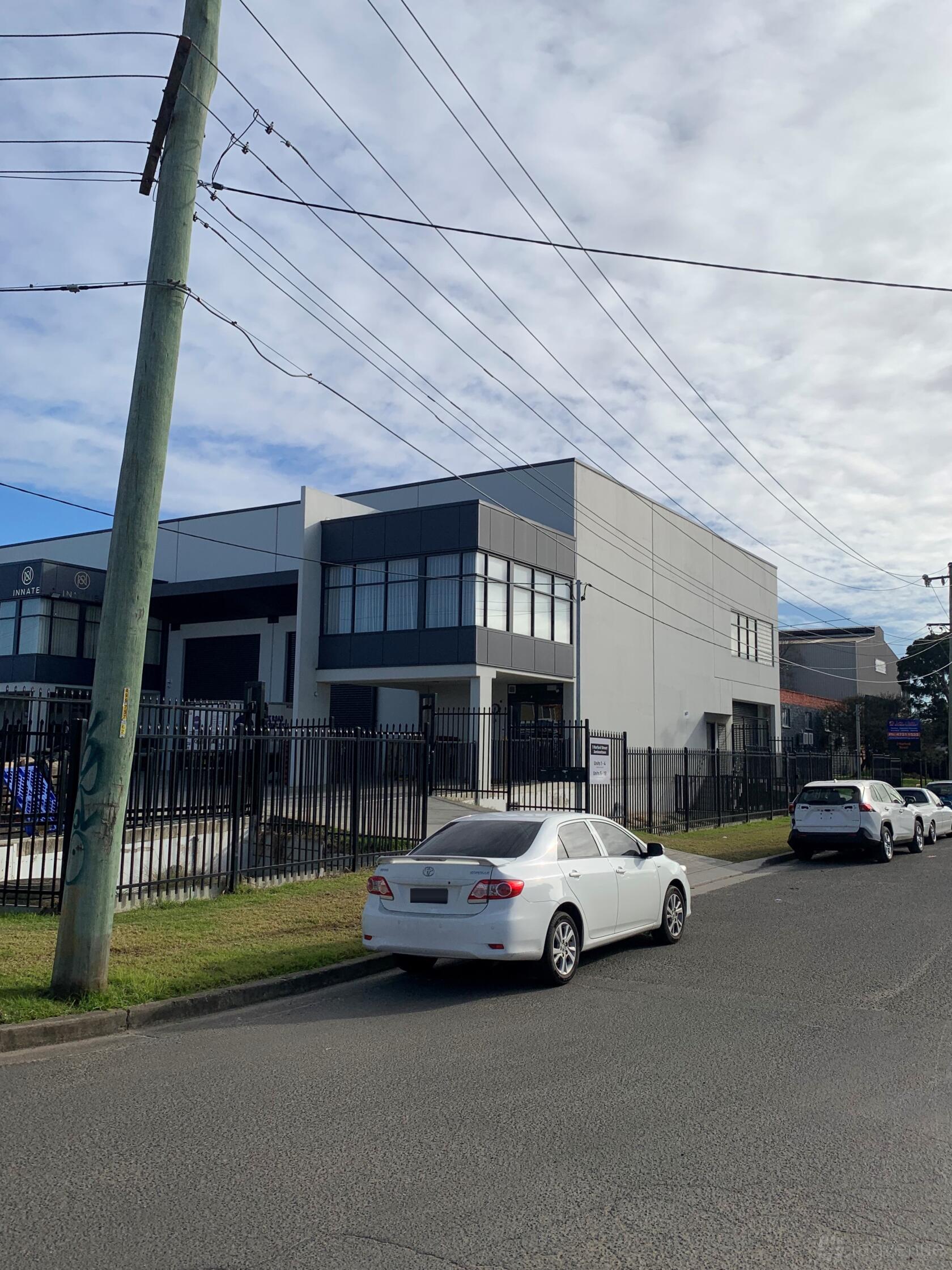 A film and photo studio with a modern gray facade, large windows, and secure fencing at Q Agency.
