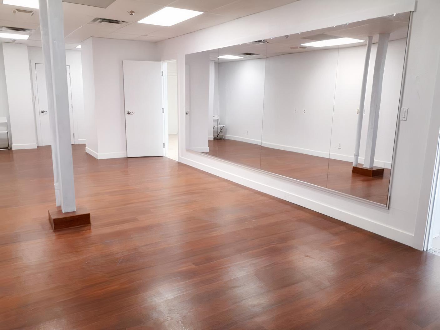 An event space in a dance studio with wood flooring, floor-to-ceiling mirrors, and white walls at Dance ConneXion Studio - Sheppard.