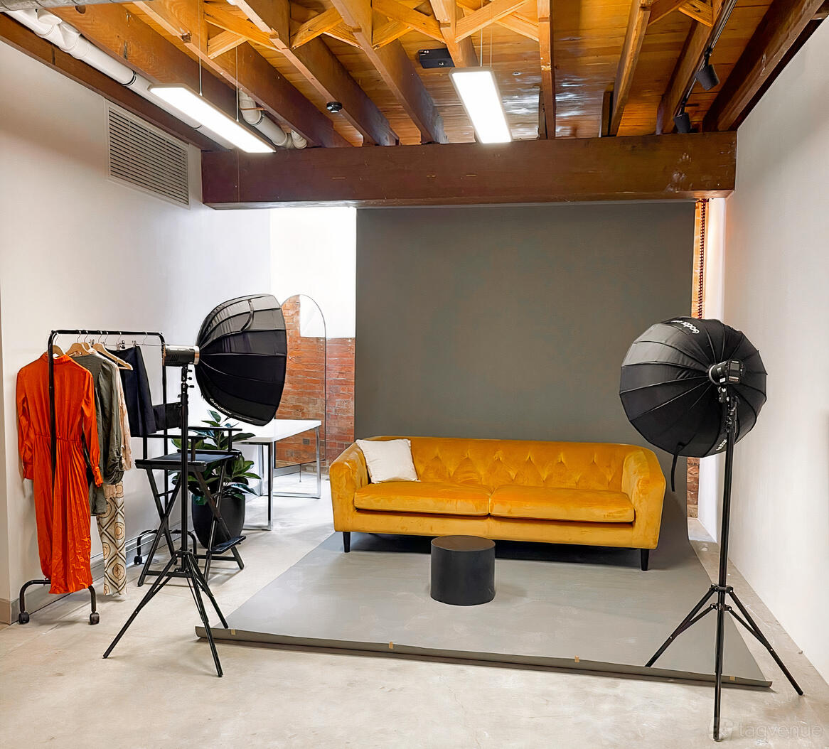 A photo studio with a mustard yellow velvet sofa, backdrop, and studio lights at eSpace Brisbane.