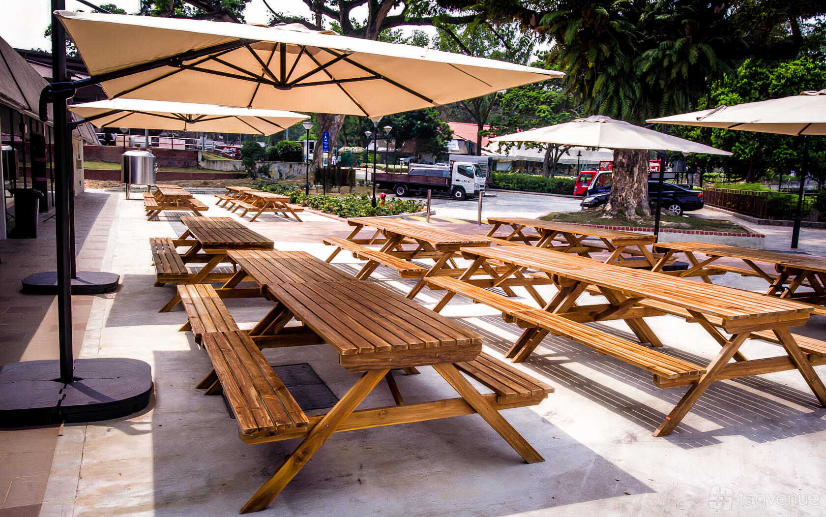 An outdoor pub area with wooden picnic tables and large umbrellas at Little Island Brewing Co. - Changi Village.