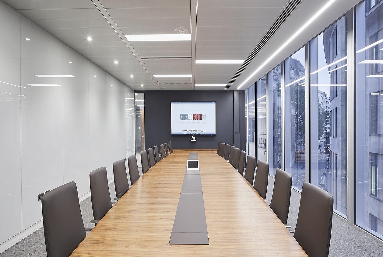 A conference centre boardroom with a long wooden table, high-back chairs, and floor-to-ceiling windows at London Conference Centre.