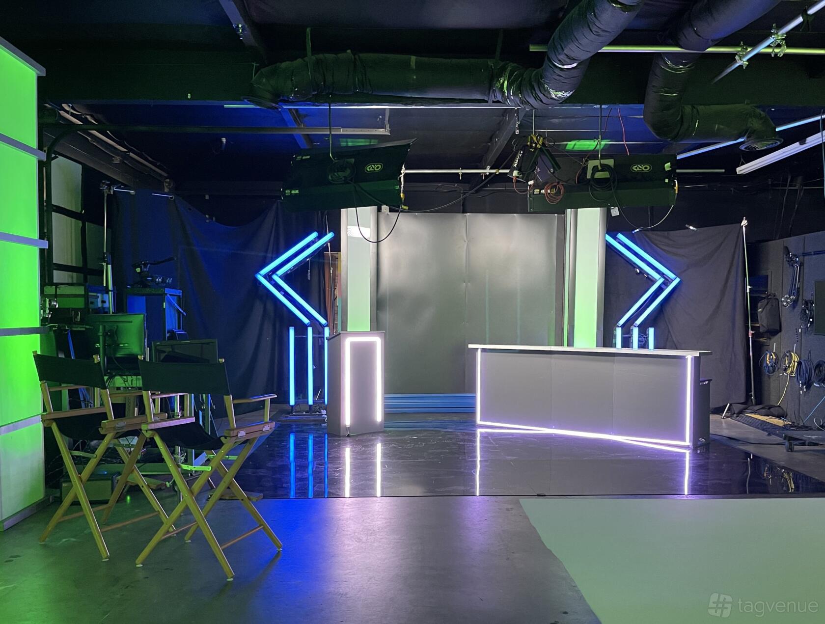 A photo studio with a game show set featuring LED accent lights, a glossy floor, and director's chairs at Super Creative.