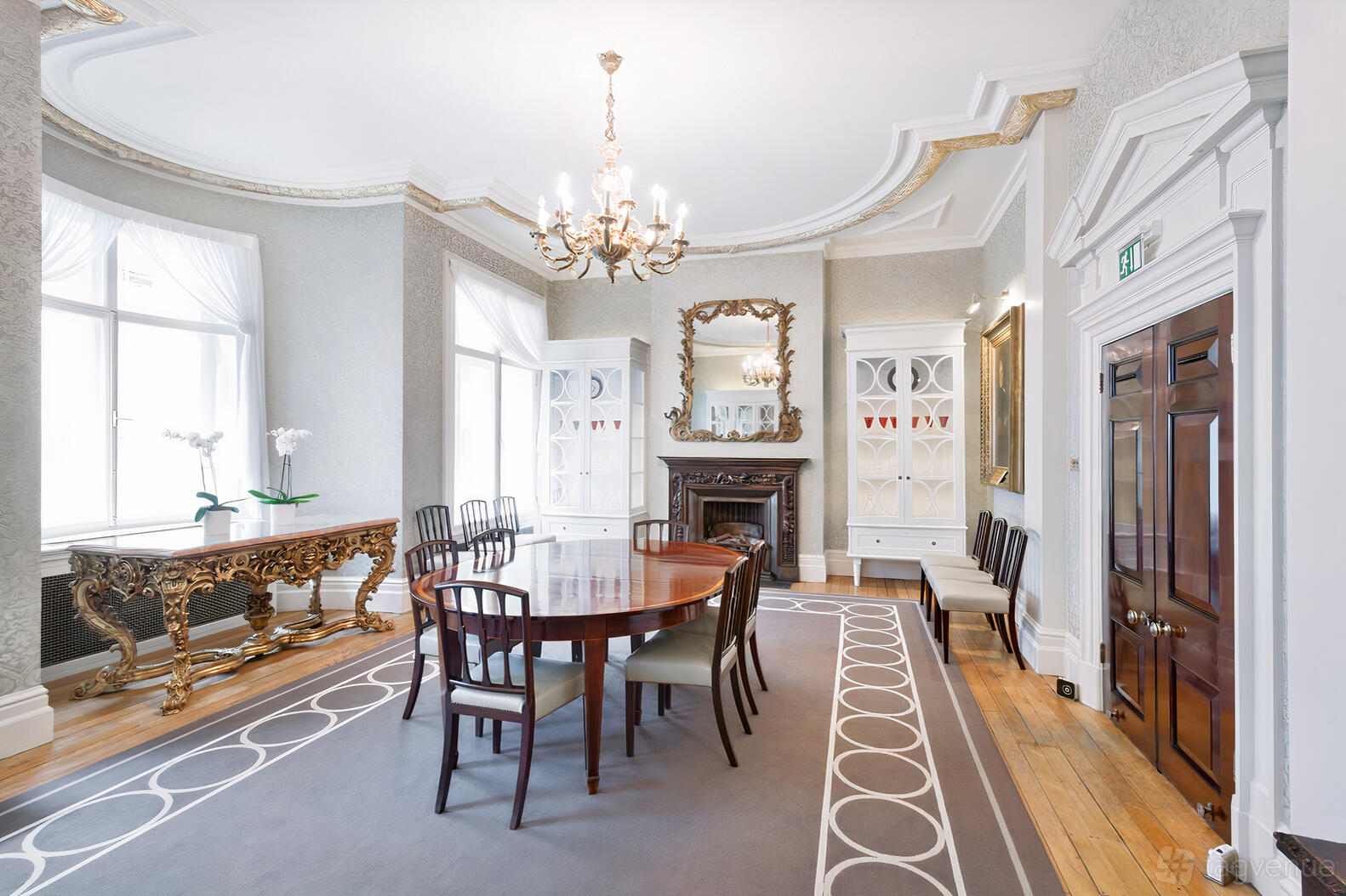 A function room with a polished wooden table, ornate gold console, and chandelier at One Moorgate Place.