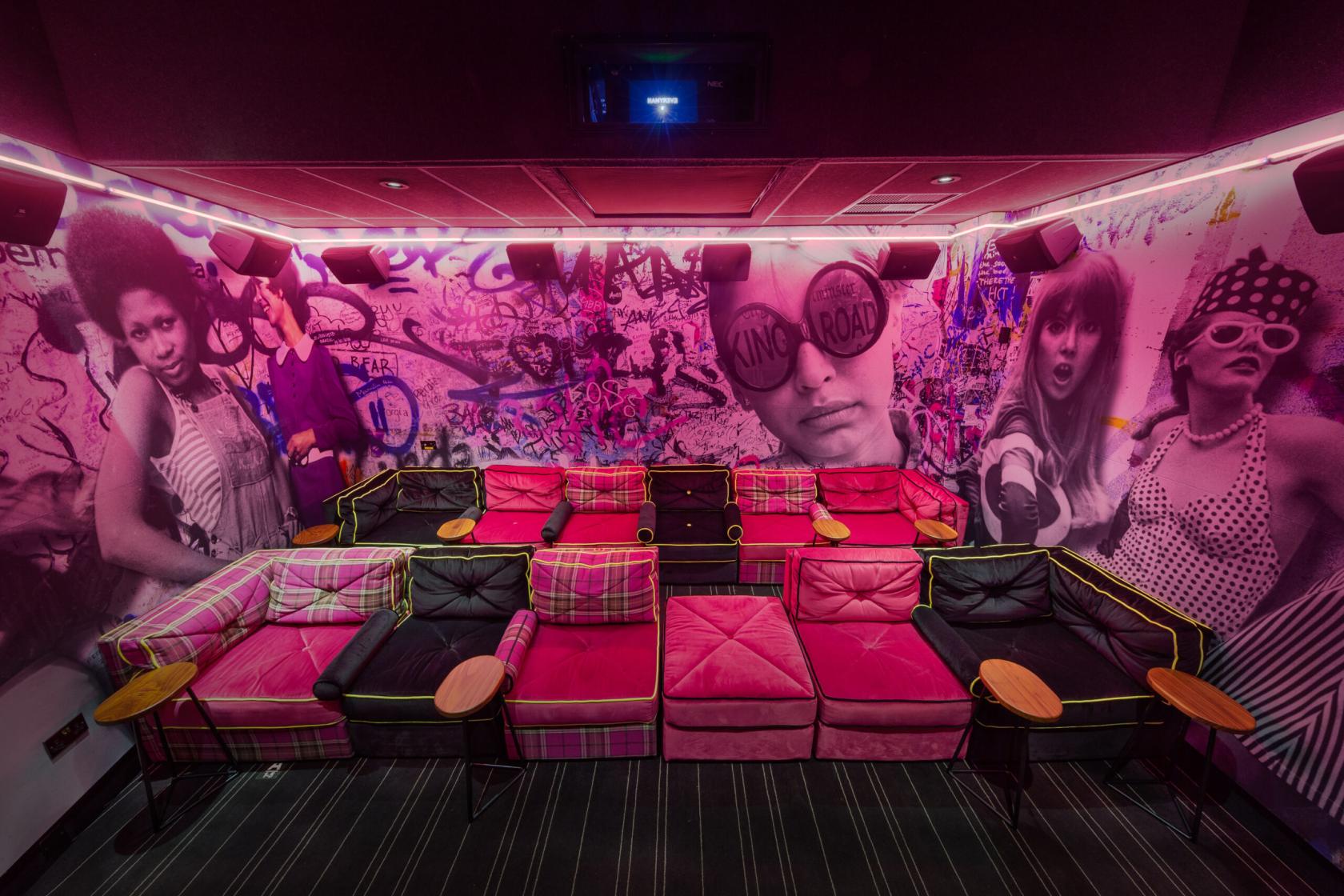 An auditorium with plush sofas, graffiti mural walls, and built-in side tables at Everyman Chelsea Screen 3.