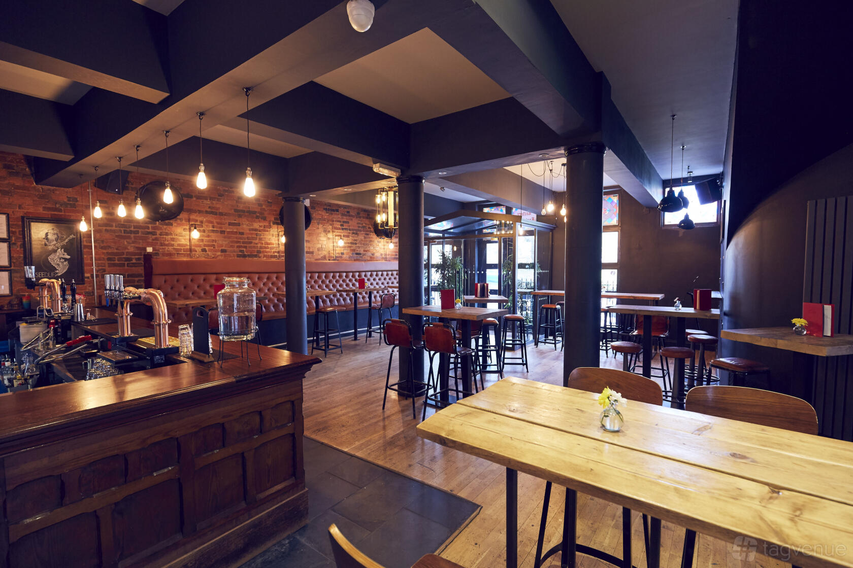 A restaurant in a pub with exposed brick walls, wood tables, and pendant lighting at The Rectory - 180 Club.