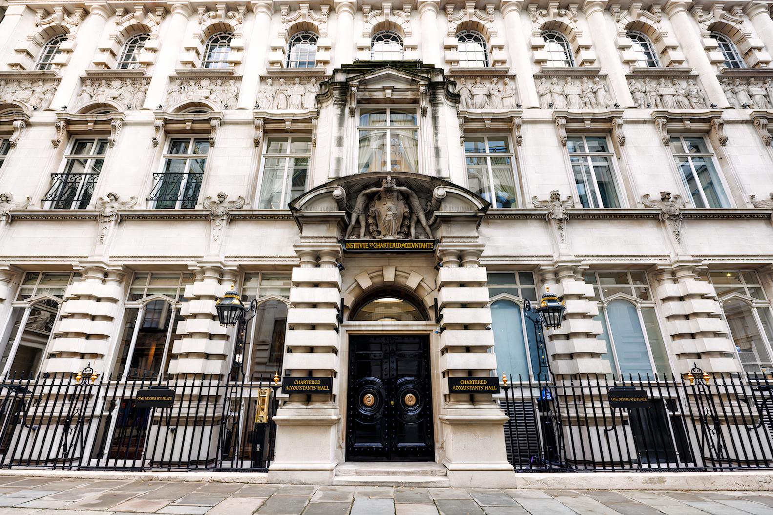 A grand building with ornate stonework, arched entryway, and intricate sculptures at One Moorgate Place.
