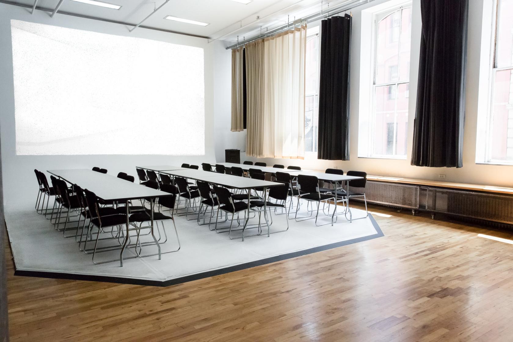 A photo studio with large windows, natural light, blackout curtains, and a central table setup at Capsule Studio NYC.