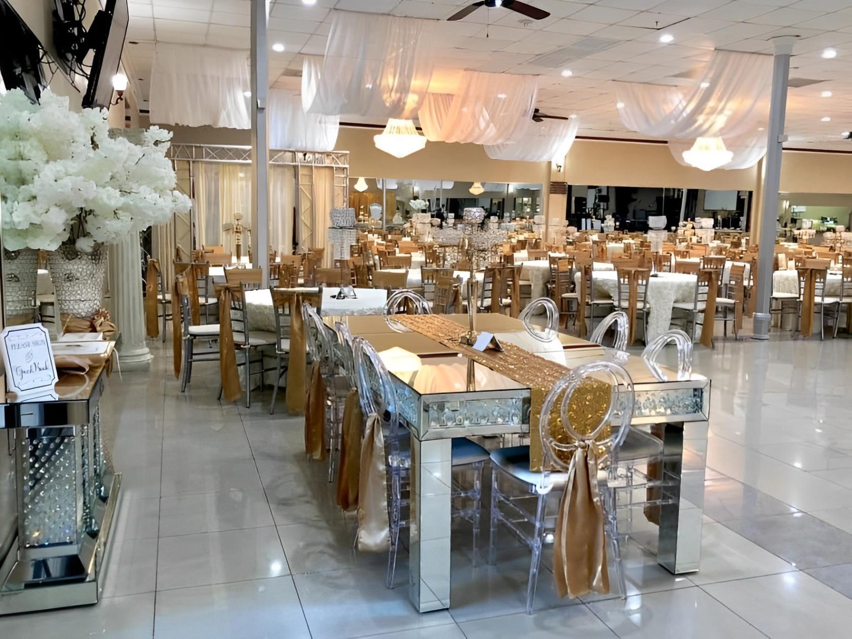 A hall with mirrored tables, clear acrylic chairs, chandeliers, and draped white fabric at Reyes Reception Hall.