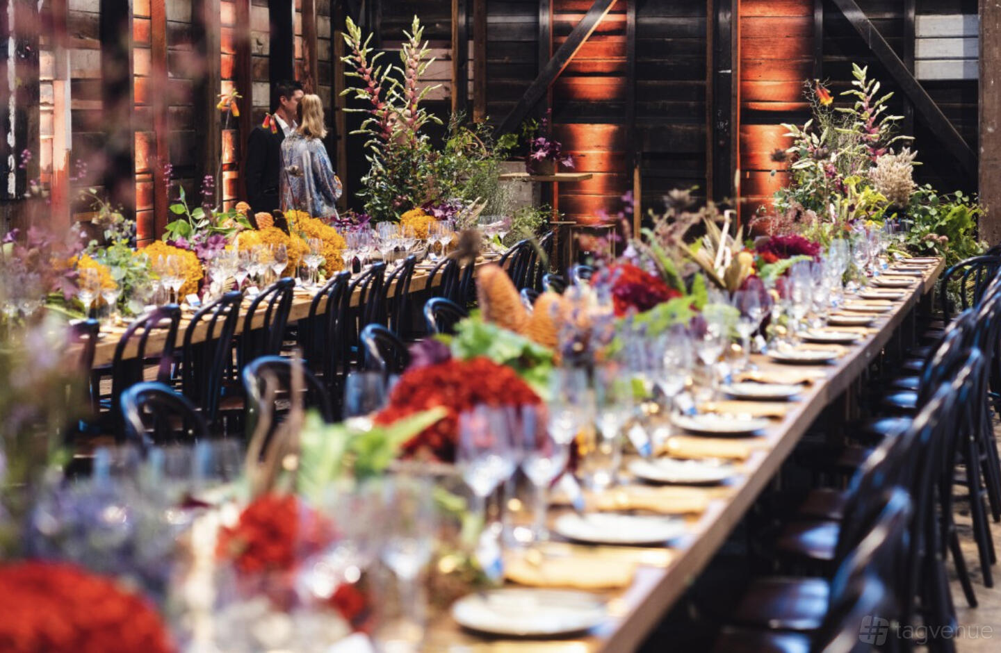 A dance studio event venue with a long banquet table, dark wood walls, and vibrant floral centerpieces at Bangarra Dance Theatre.