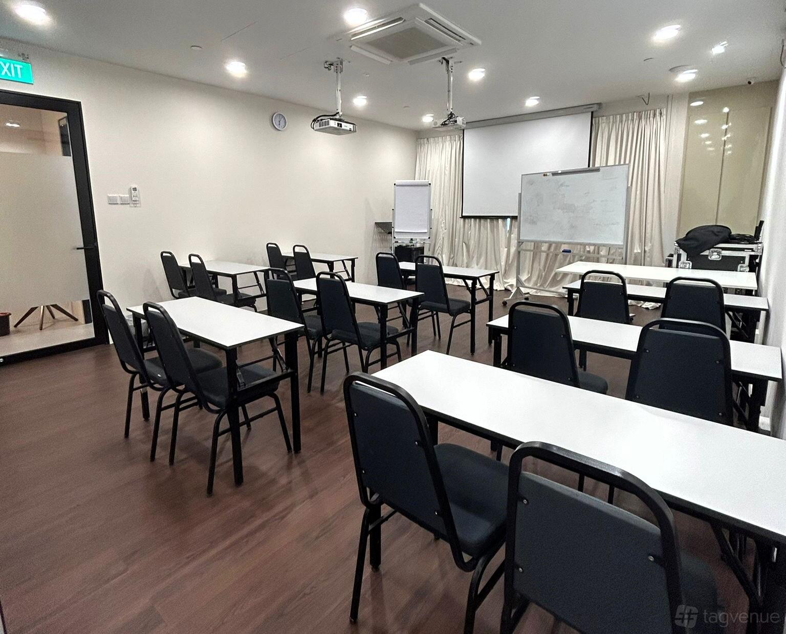 A meeting room with rows of black chairs, white tables, a projector, and a whiteboard at Meeting Room Rental Singapore.