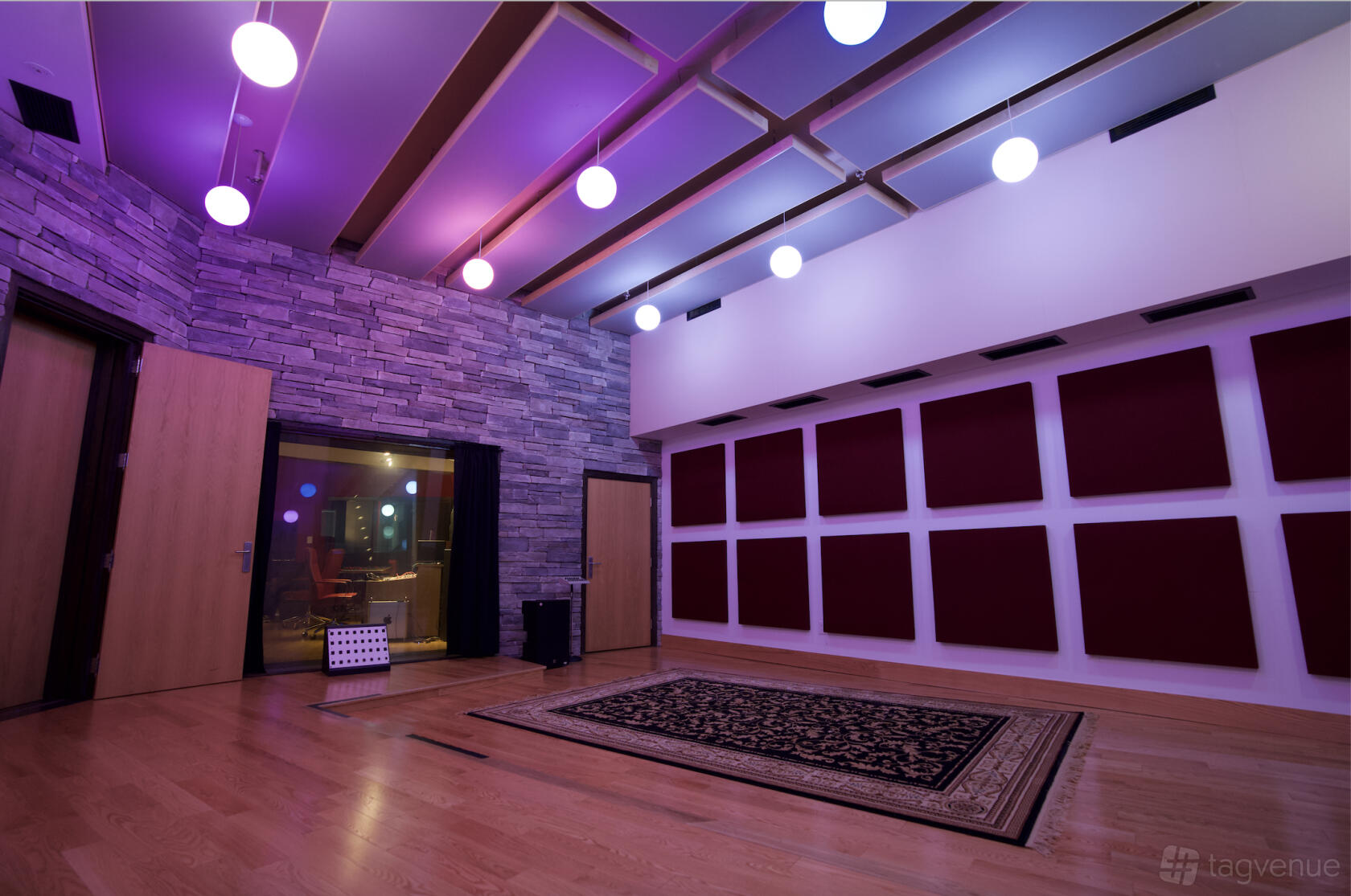 A rehearsal room with wood floors, acoustic wall panels, and stone accents at Abstract Studios.