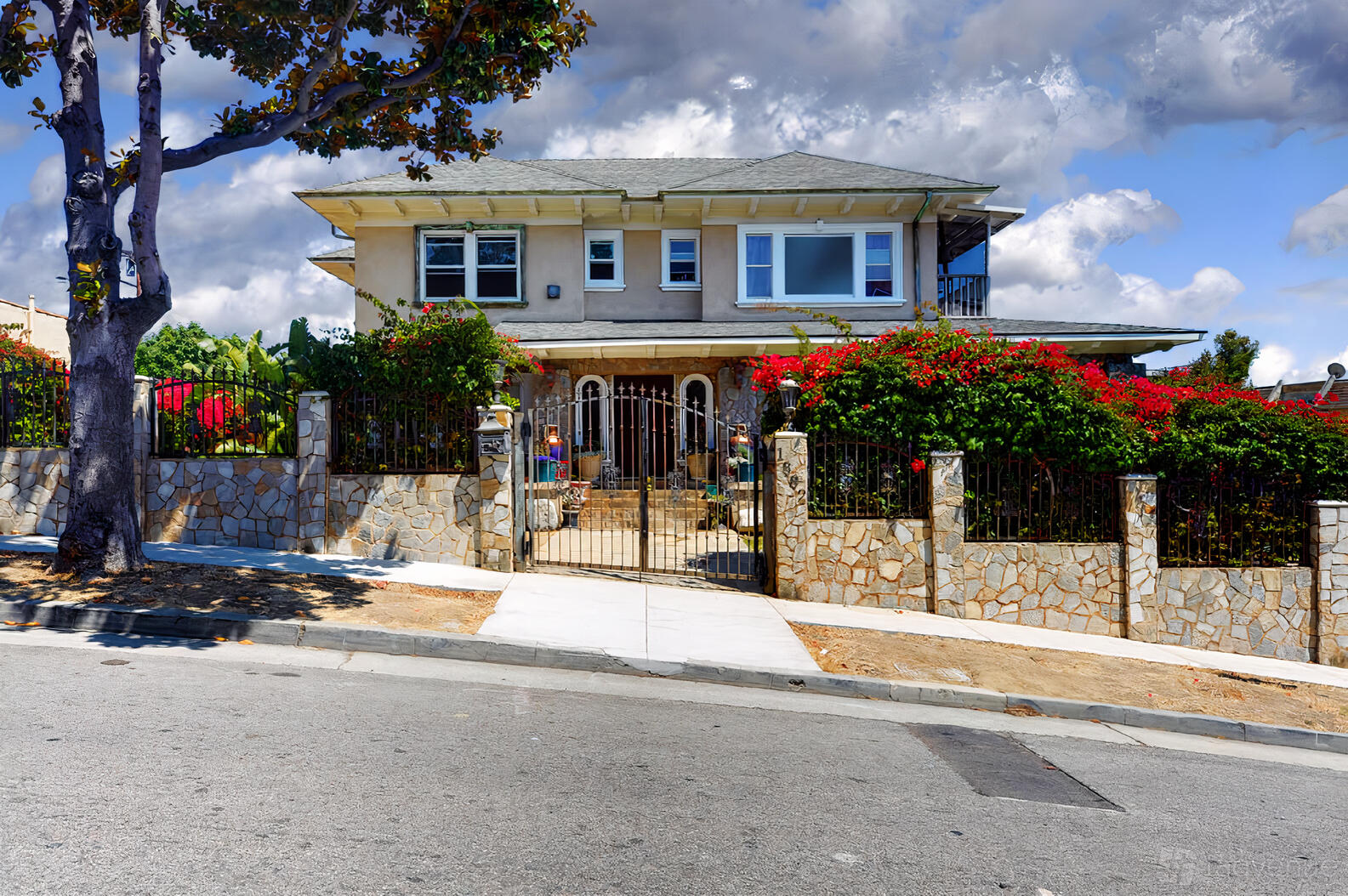 A recording studio with a gated stone entry, lush greenery, and a two-story house exterior at Private Island Audio.