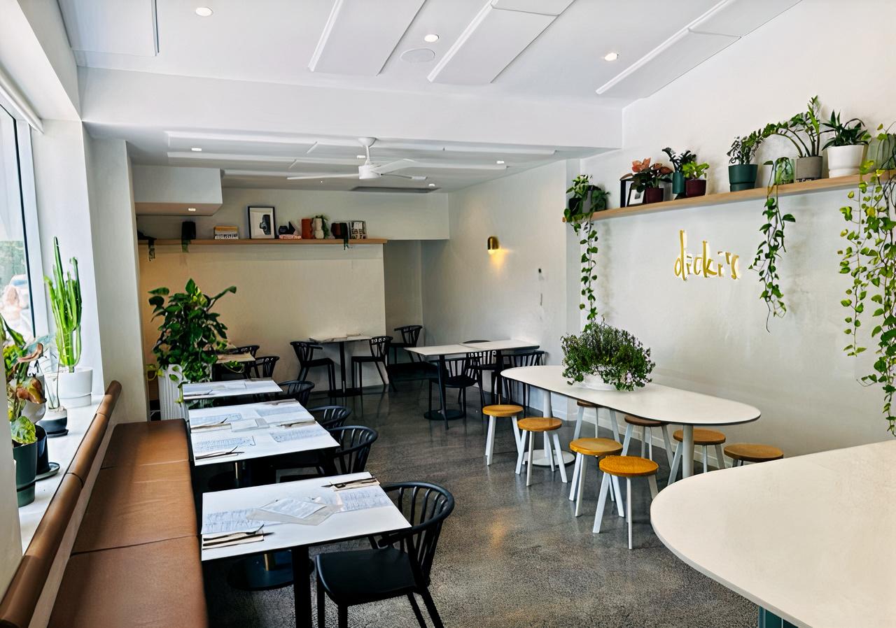A cafe with polished concrete floors, white tables, black chairs, and greenery at Dicki's Ascot.