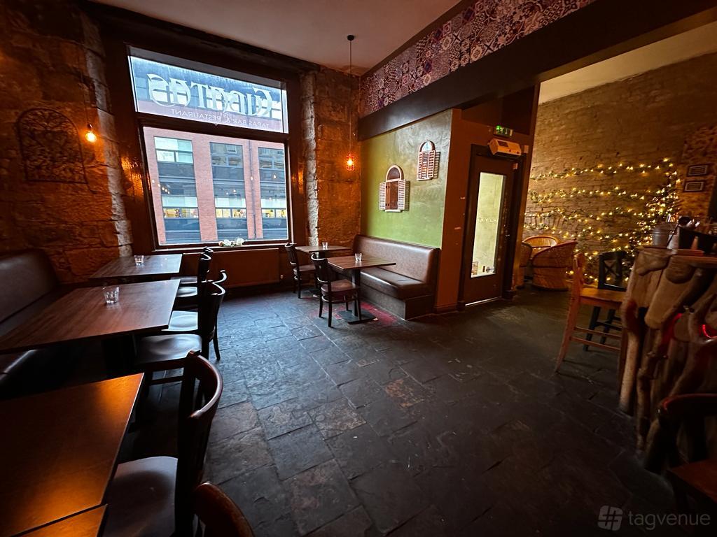 An event venue with exposed stone walls, string lights, and large windows at 91B Mini.