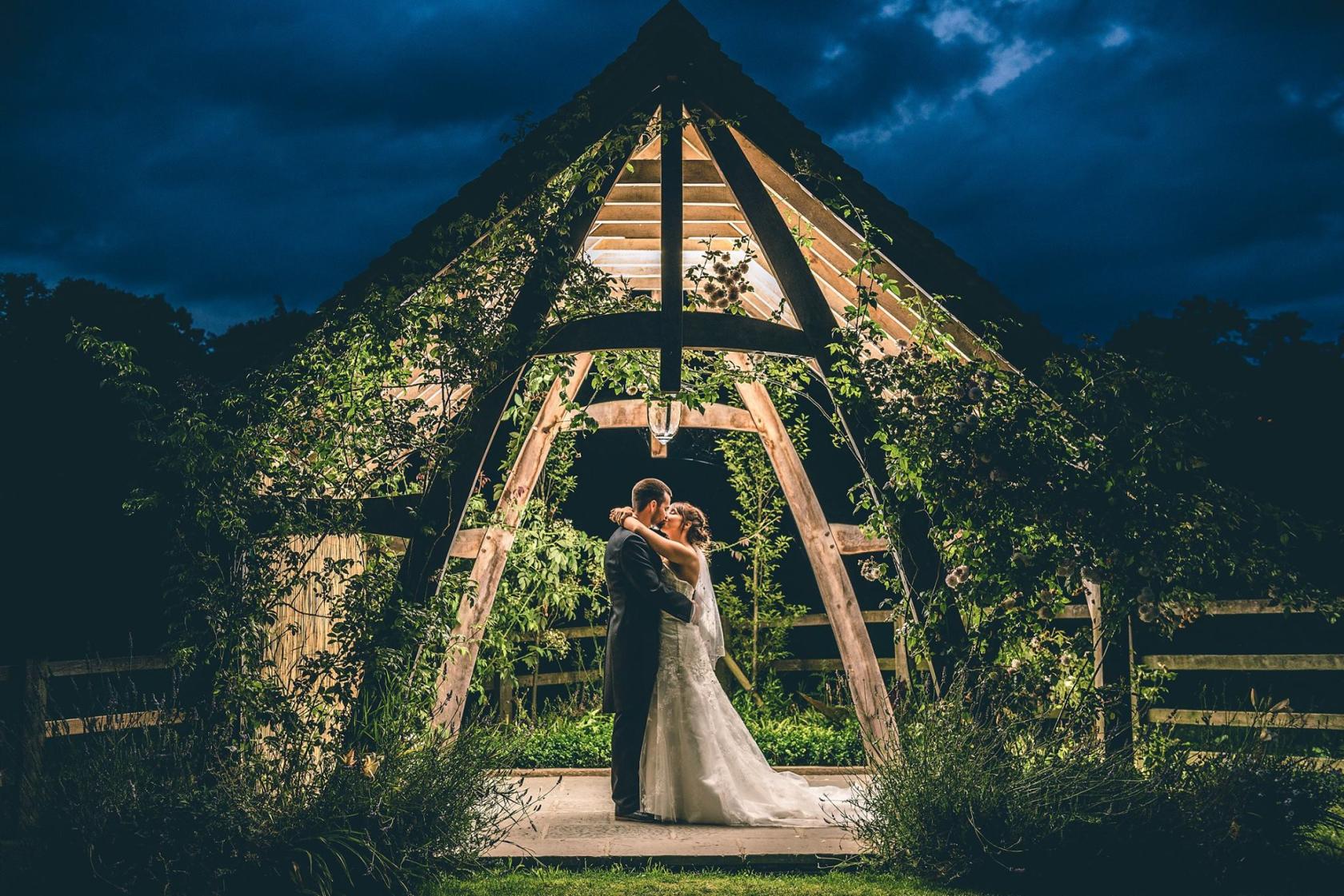 An event venue with a wooden open-air pavilion framed by greenery and a hanging pendant light at Hyde House.