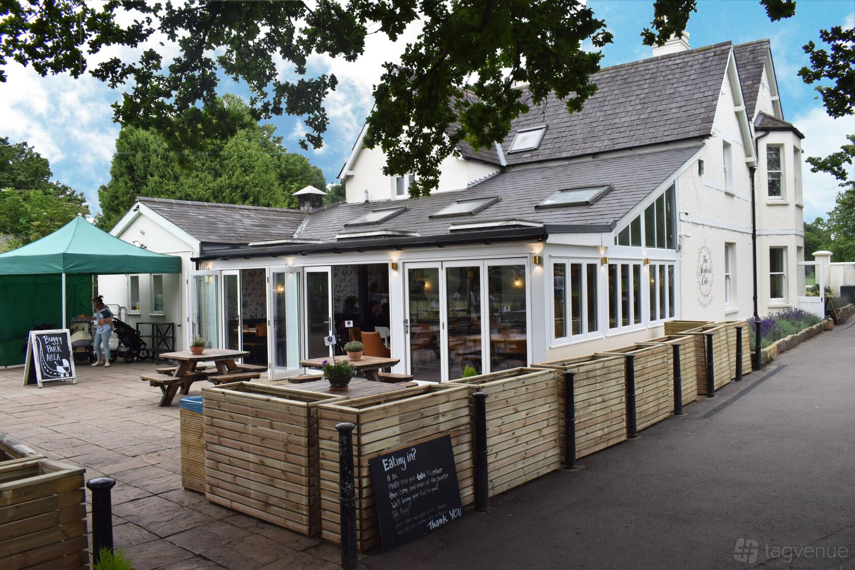 A café with an outdoor patio, wooden fencing, picnic tables, and a green tent at The Skylark cafe.
