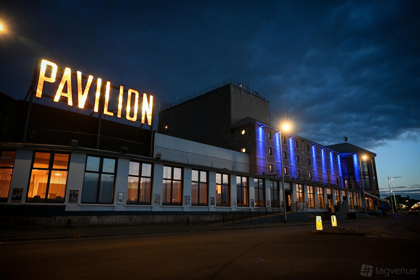 An event space exterior with large illuminated 'Pavilion' sign and blue accent lighting at Weymouth Pavilion.