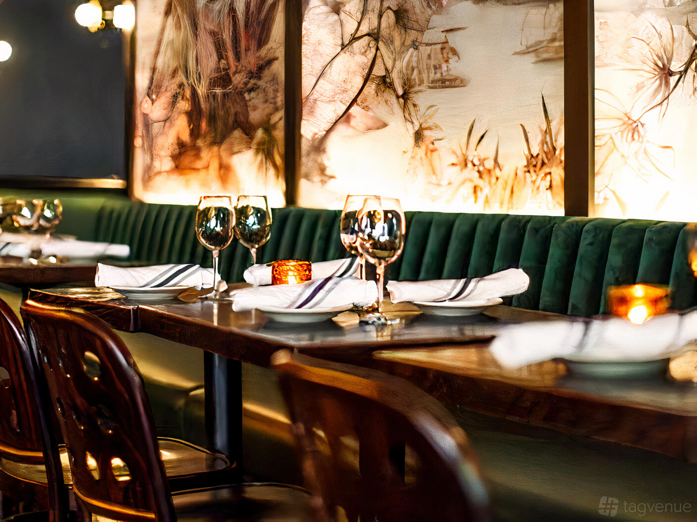 An event space in a bar with green velvet banquette seating, wood tables, and set wine glasses at 5th and Mad.