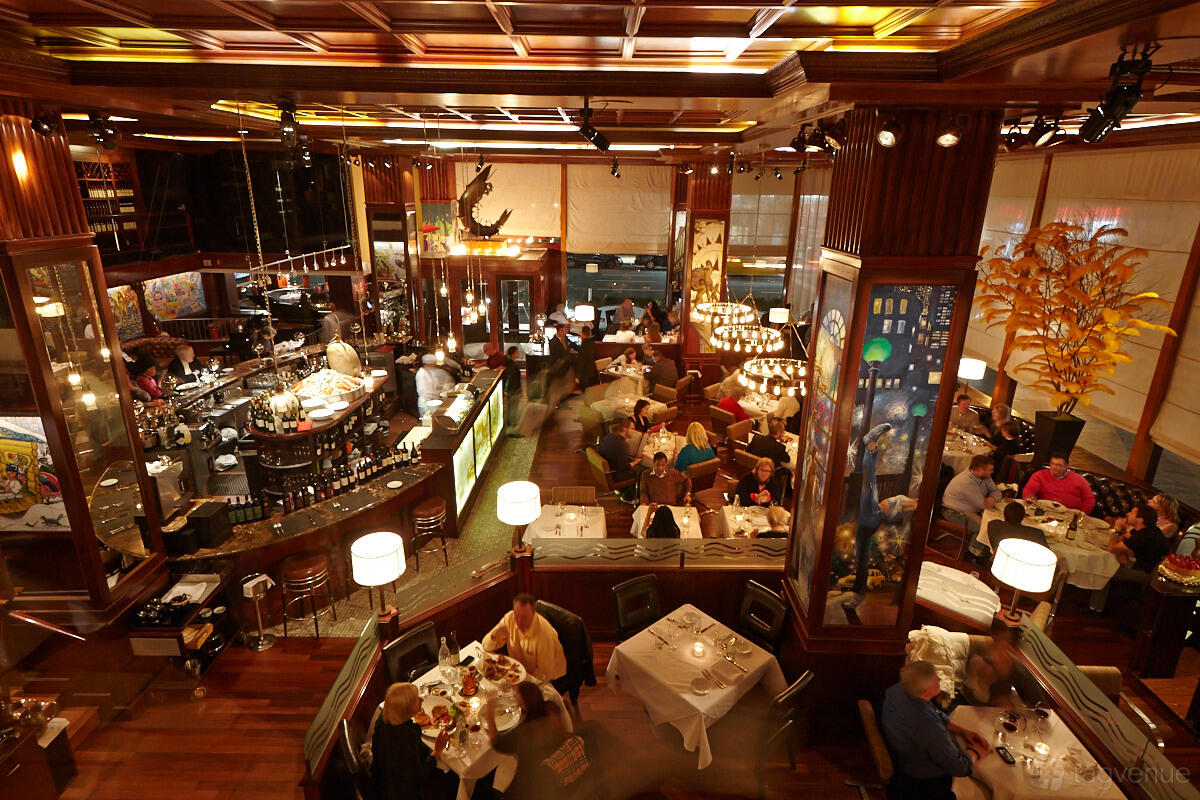 A restaurant with wood-paneled walls, white tablecloths, and ambient pendant lighting at Redeye Grill.