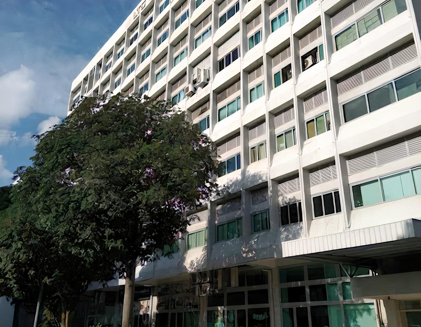 A multi-story building with large windows and a flowering tree in front at Noooice! Academy.
