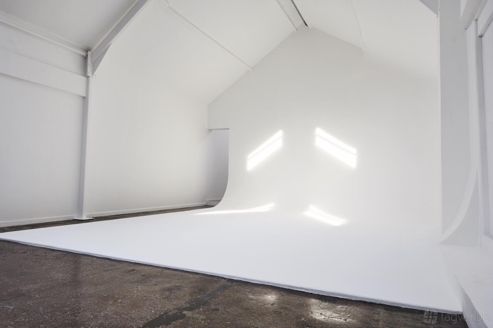 An event space with high vaulted ceilings, white cyclorama walls, and polished concrete floors at fivefourstudios.
