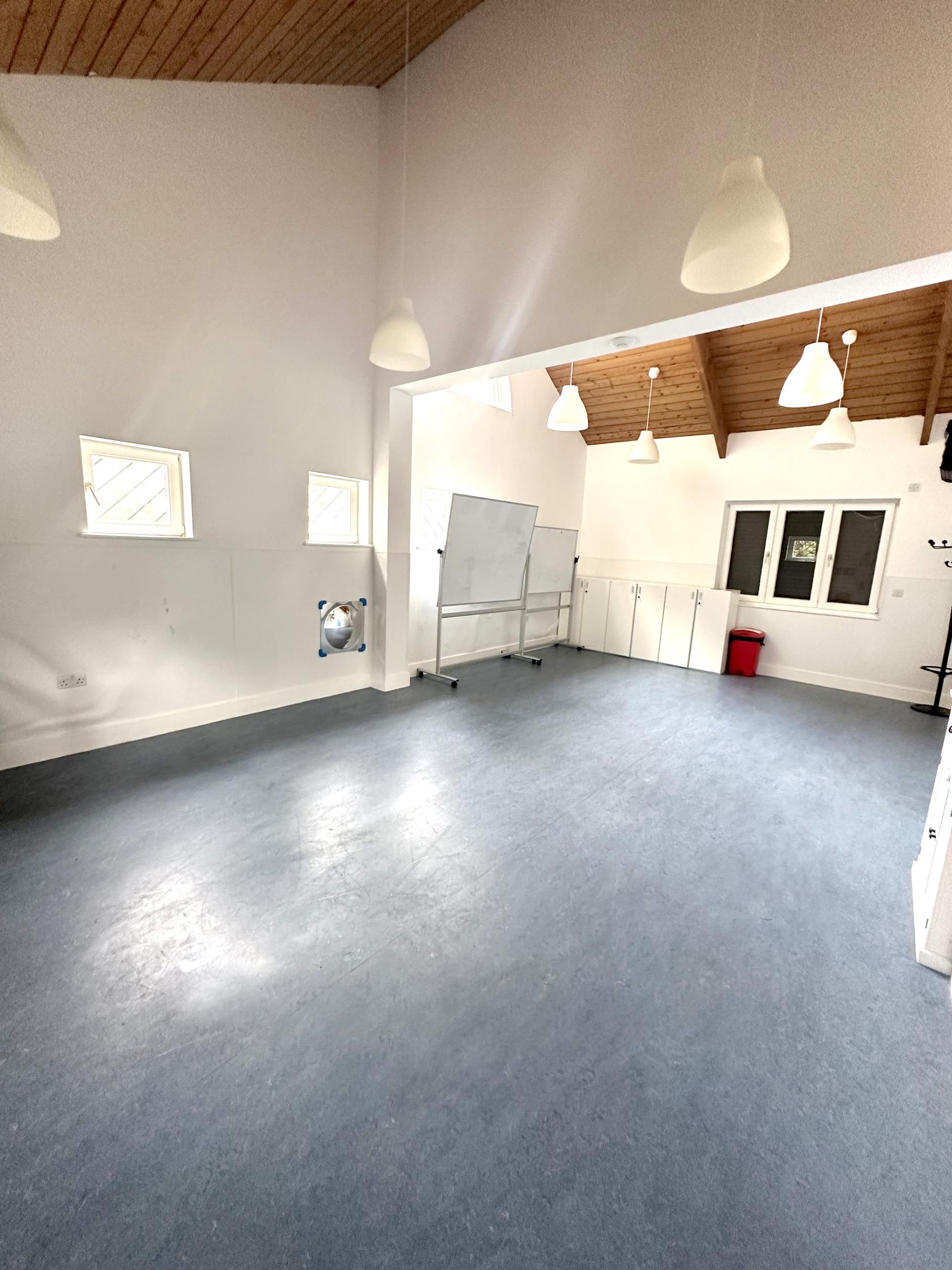 An event space with high ceilings, white walls, skylights, and a mobile whiteboard at Castlehaven Community Centre & Hub.