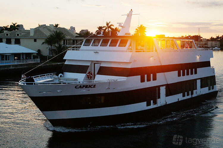 A charter boat with multiple decks, large windows, and outdoor seating at Lots Of Yachts/Lots Of Spots South Florida.