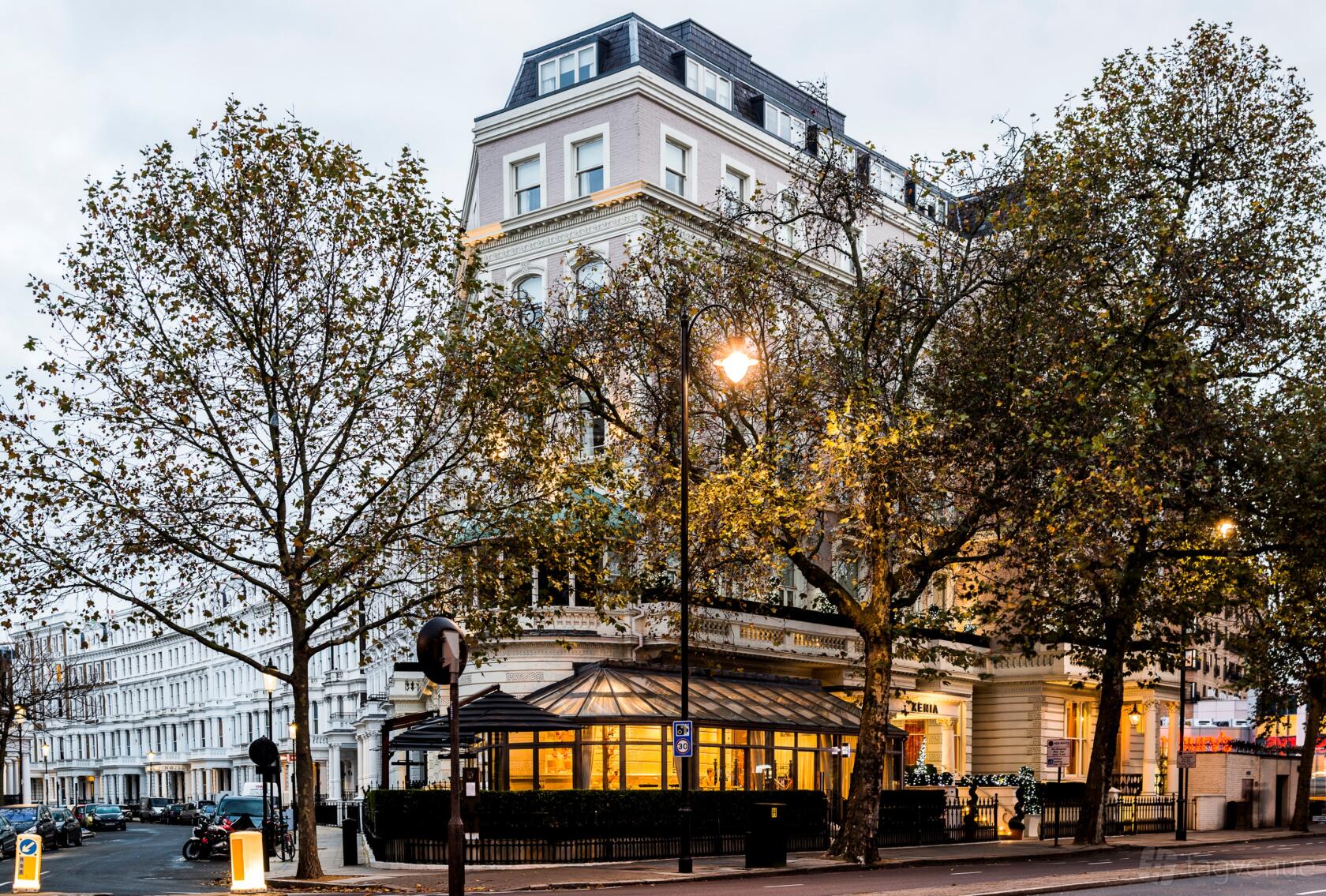 A restaurant with a glass-enclosed patio and street-facing facade beneath mature trees at La Terrazza.