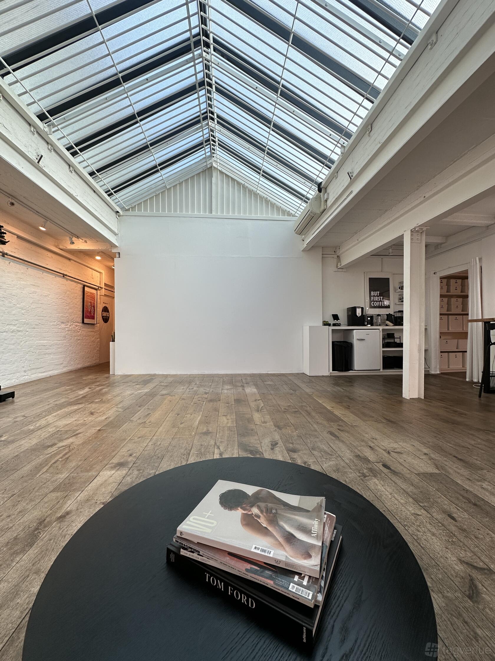 A photo studio with skylights, white brick walls, and wood flooring at SW10 Studios.