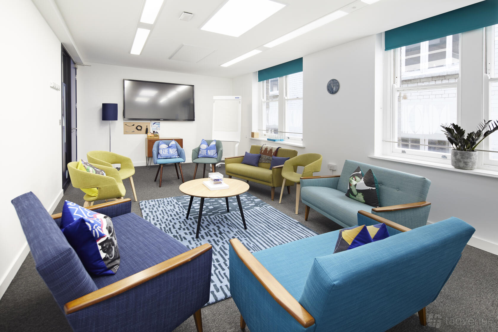 An event venue with colorful armchairs, a round coffee table, and large windows at Wallacespace Covent Garden - 53 Parker Street.