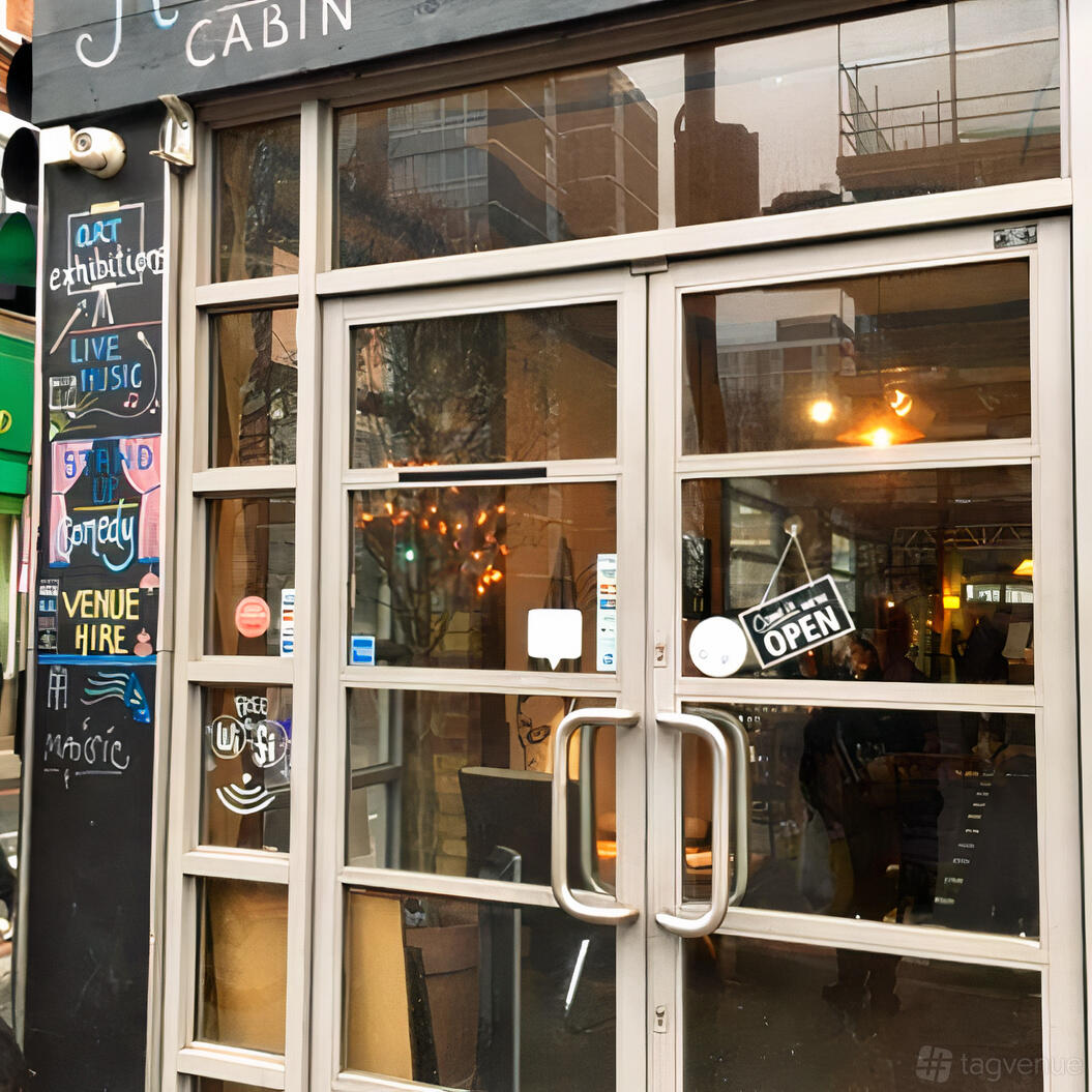 A pub entrance with glass double doors, chalkboard event listings, and warm lighting inside at Hoxton Cabin.