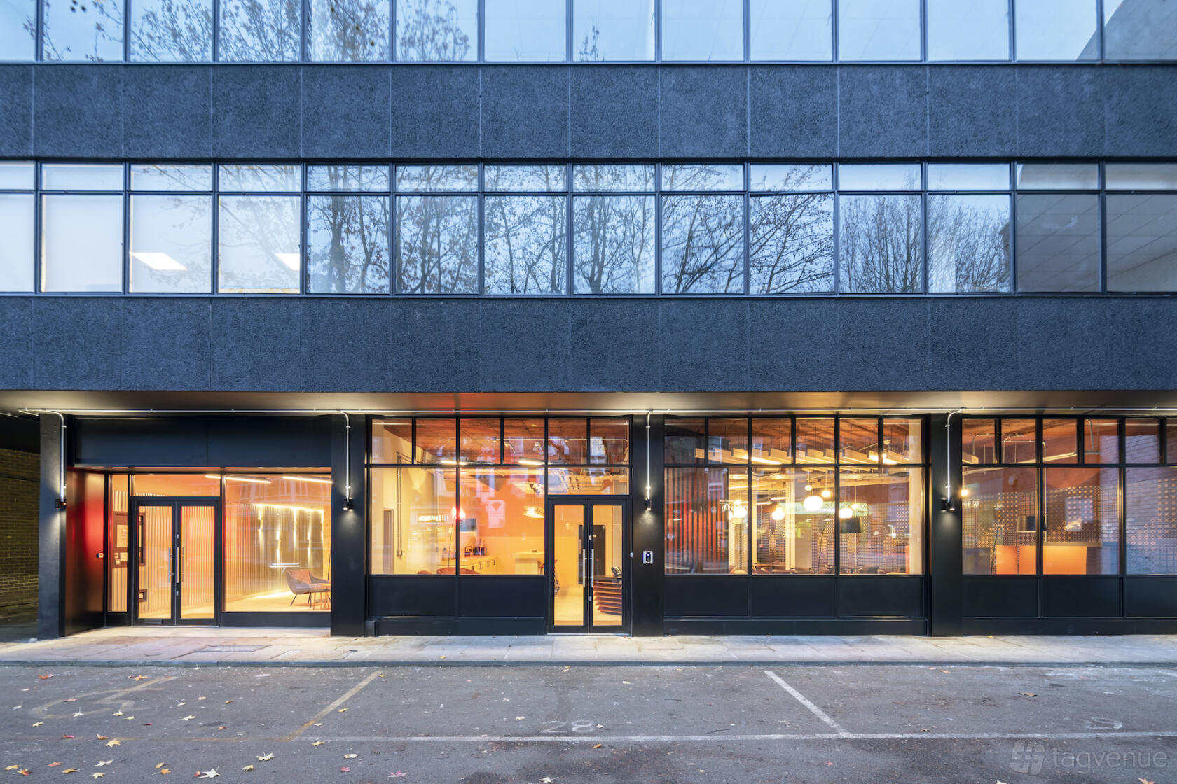 A meeting centre with tall windows, glass doors, and warm interior lighting at Saunders House