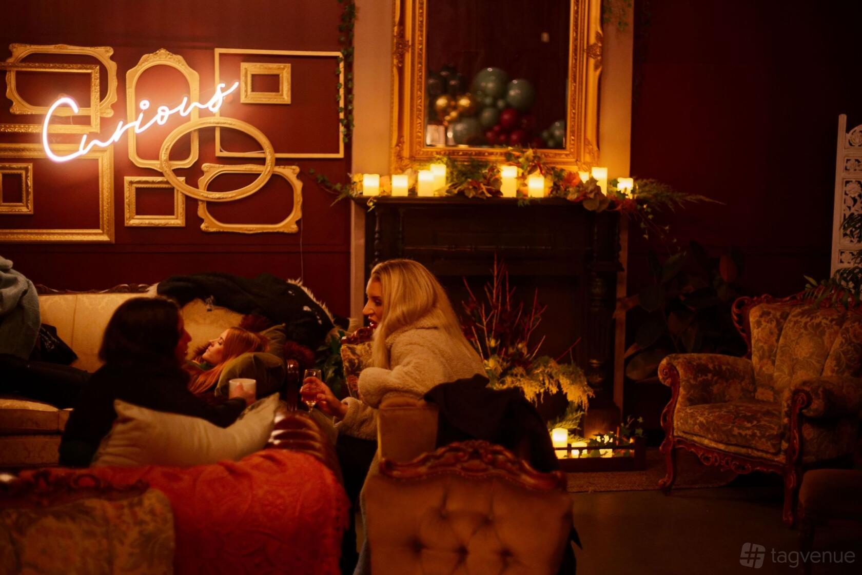 An event space with vintage sofas, candlelight, neon signage, and ornate mirrors at Curious Events Co.
