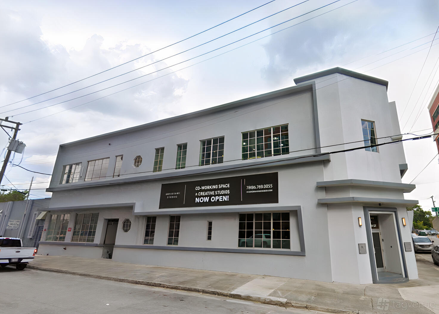 A meeting centre with a white facade, large industrial windows, and a prominent entrance at Ampersand Studios.