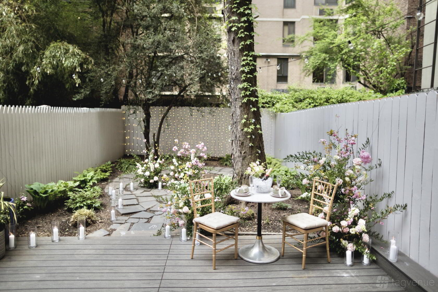 A garden with stone pathways, string lights, and a bistro table surrounded by lush plants at Sahola Flowers.