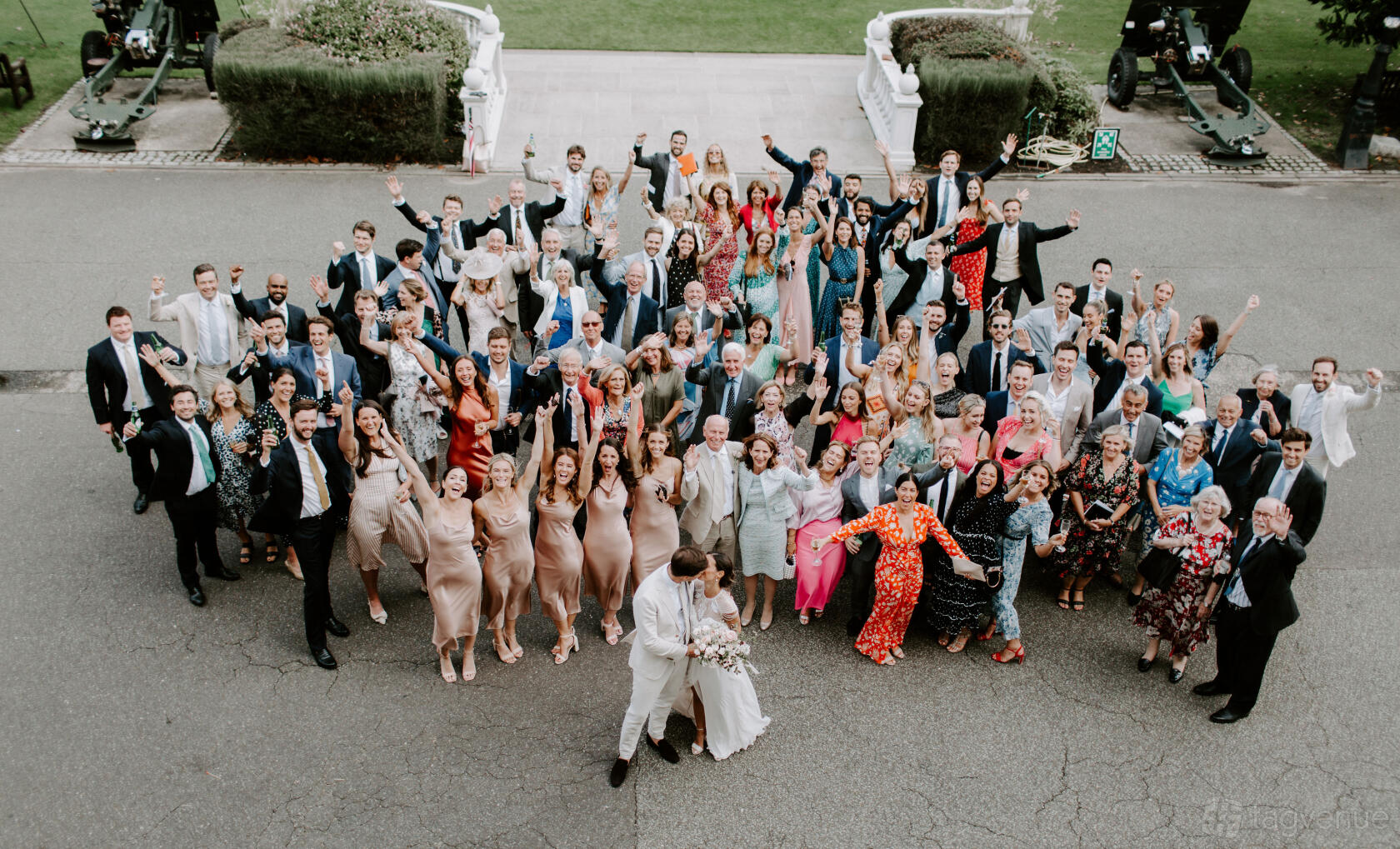 An outdoor event venue with a large group of wedding guests gathered on a paved area at The HAC Prince Consort Rooms.