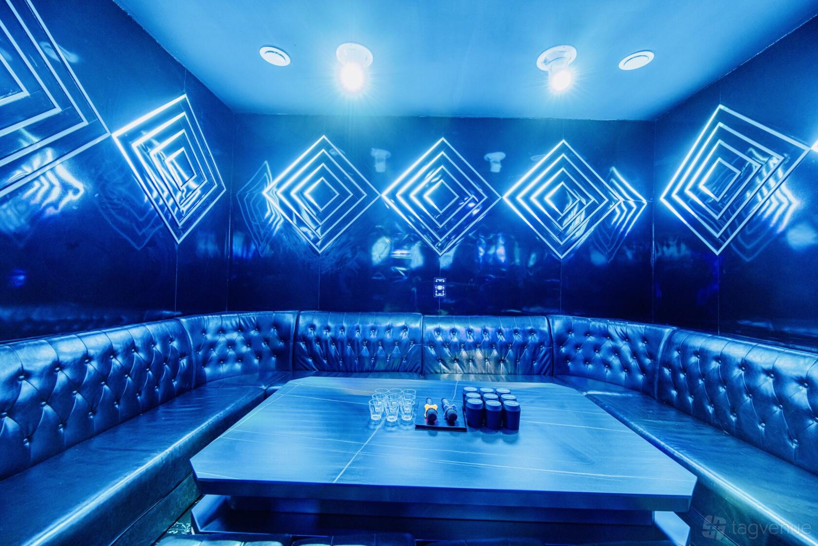 A karaoke function room with tufted leather seating, geometric wall lights, and a central table at G-Funk KTV.